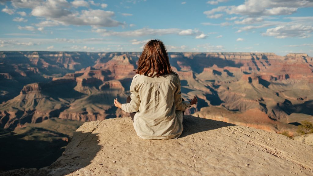 Woman meditating on the edge of a canyon
