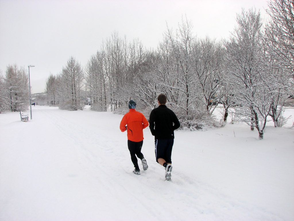 Two people running down a snowy trail 