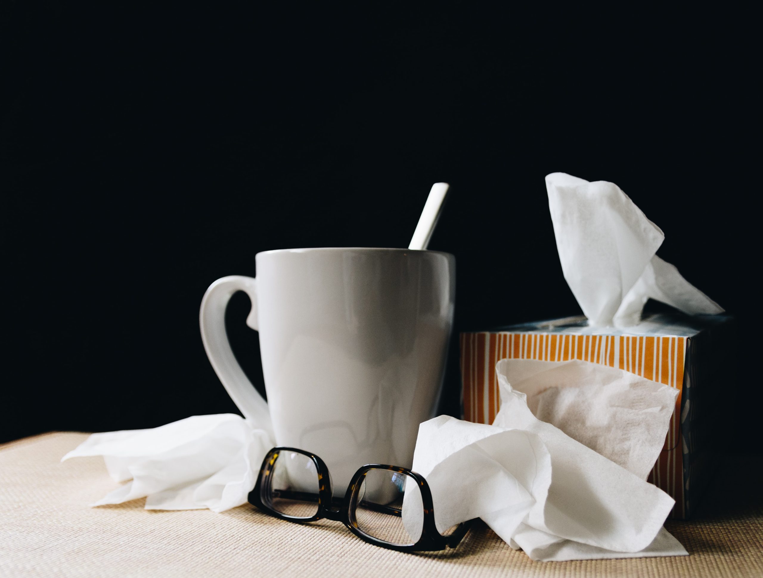 A cup, tissues, and glasses for someone who is recovering from sickness