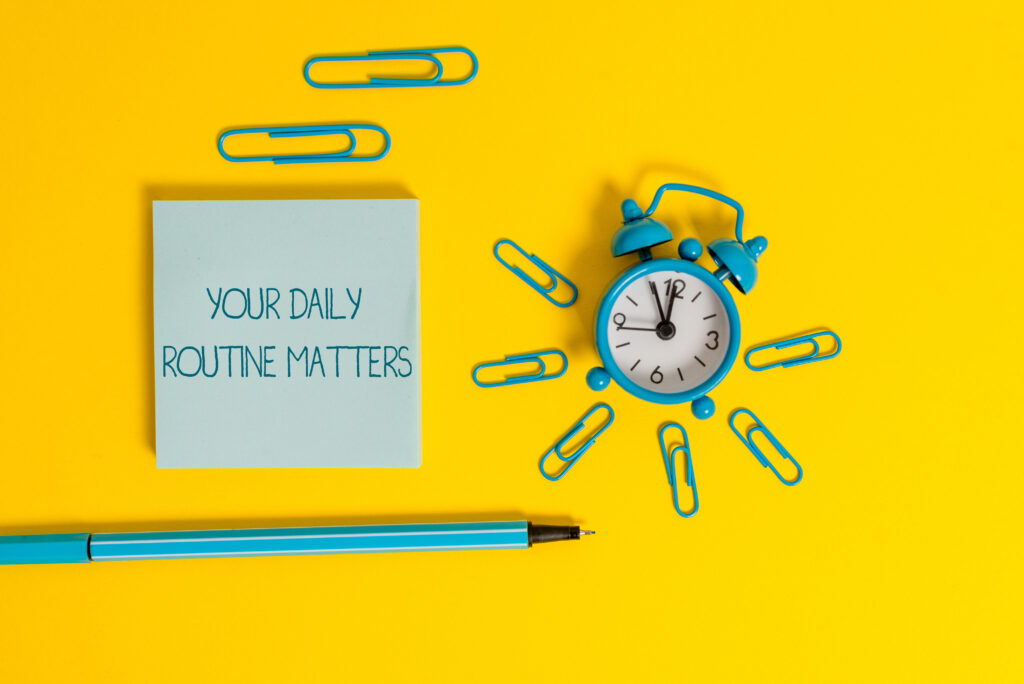 Word writing text Your Daily Routine Matters. Business photo showcasing practice of regularly doing things in fixed order Metal alarm clock wakeup clips ballpoint notepad colored background